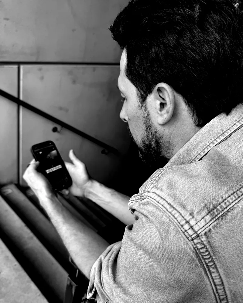 Martin Krenn auf einer Treppe, tippt etwas in sein Telefon.